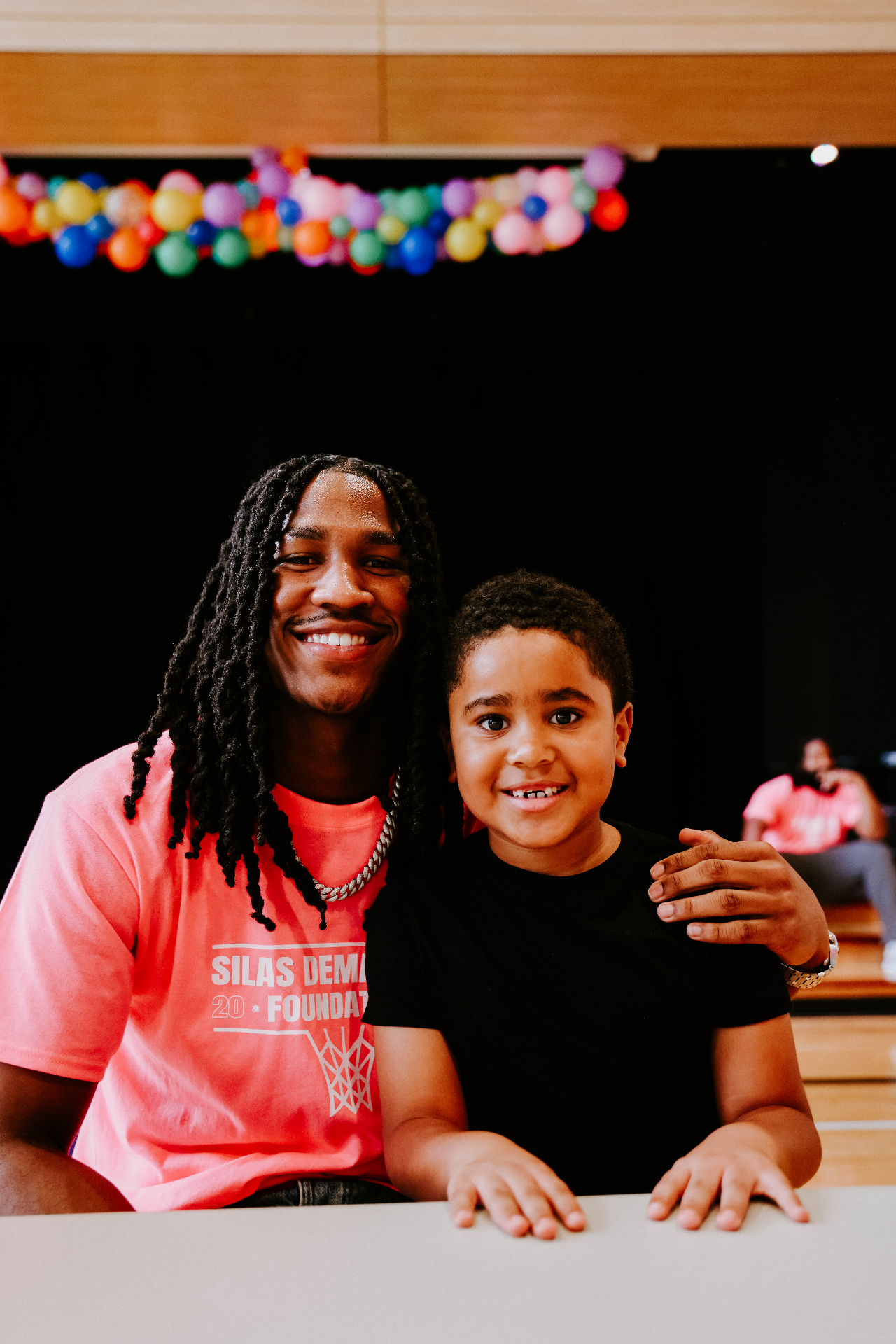 Silas smiling with a young boy at a foundation event